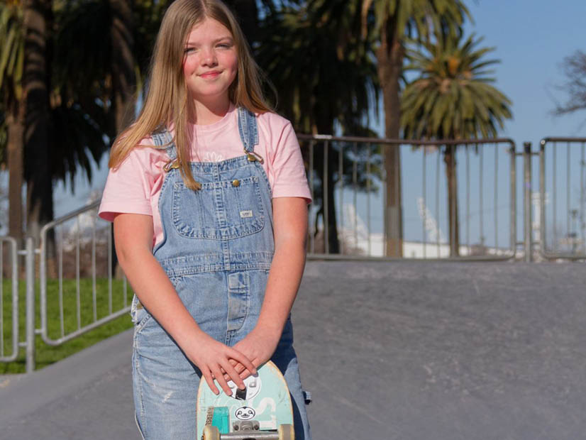 Girl standing holding her skateboard up at Riverslide Skate Park.
